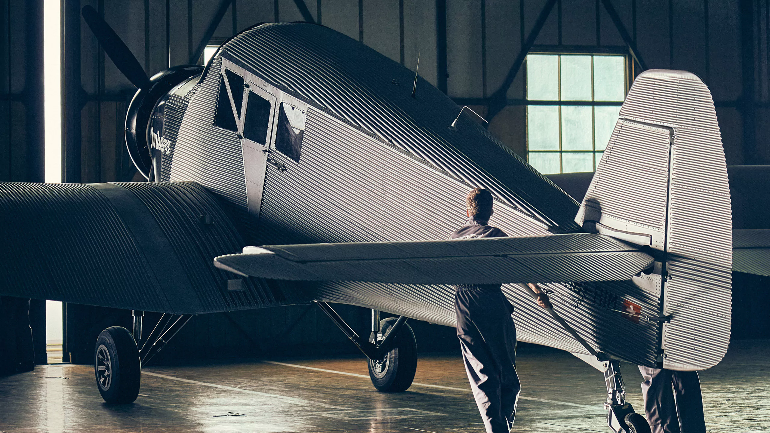 Eine Aufnahme von einem Mann der ein Junkers F13 Flugzeug aus dem Hangar schiebt