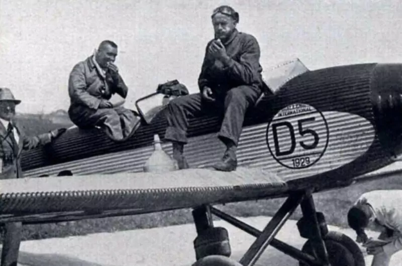 Eine historische Aufnahme von zwei Piloten, die auf einem Junkers A50 Junior Flugzeug sitzen und essen